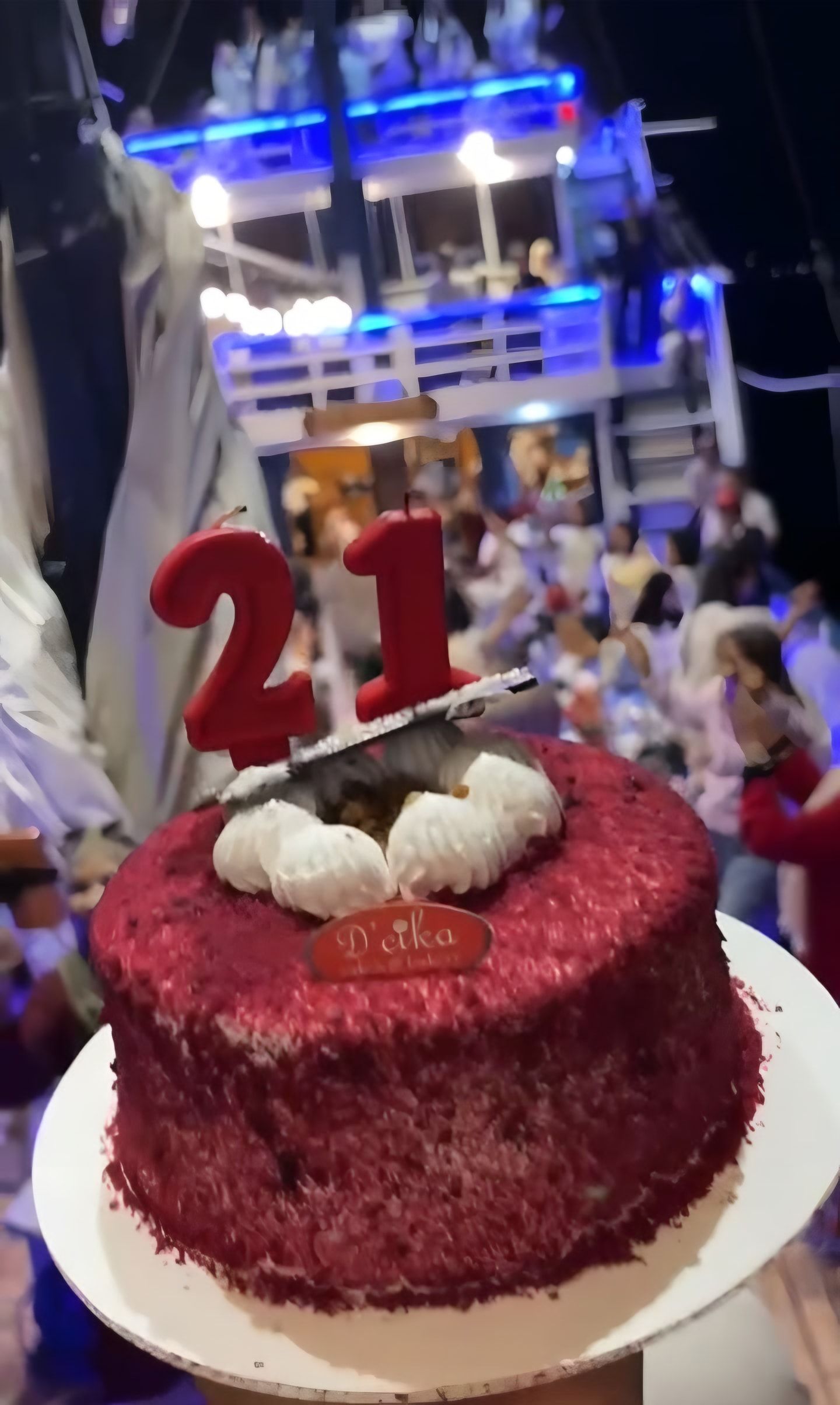 Kue ulang tahun red velvet dengan lilin angka 21 di atas kapal pada malam hari