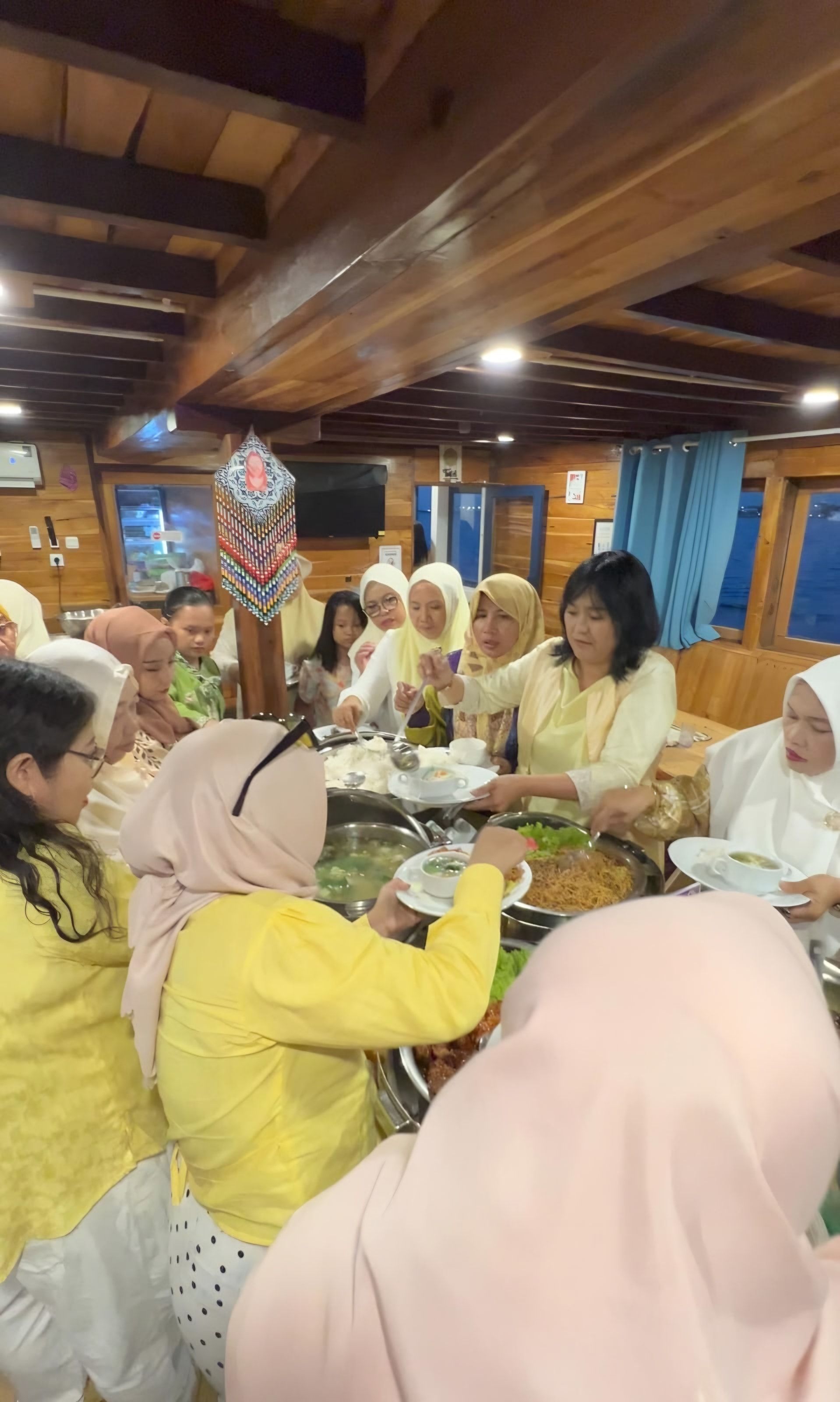 Tamu private trip mengambil hidangan prasmanan di kabin kayu kapal