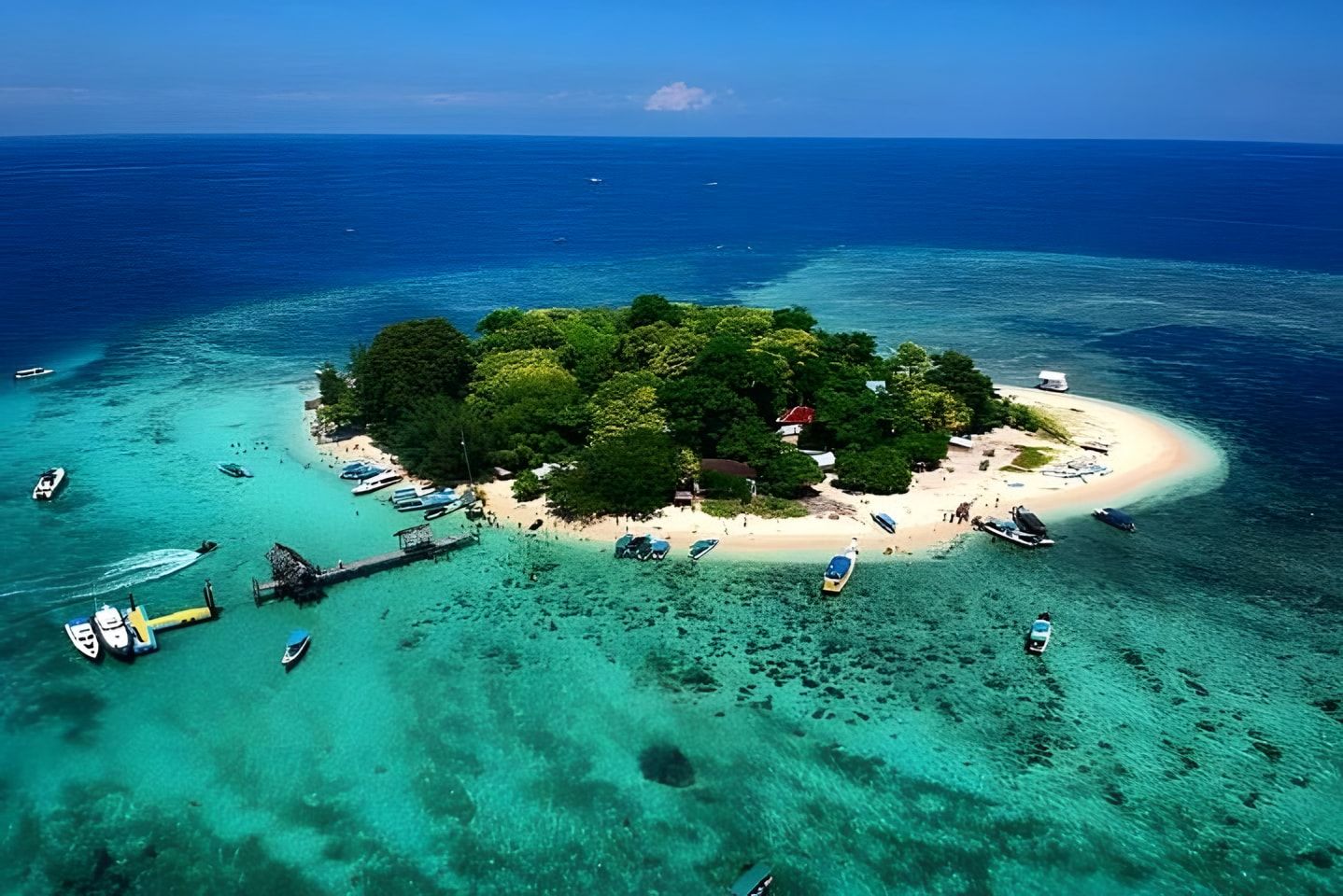 Pulau Samalona dilihat dari udara, dikelilingi air toska dan terumbu karang